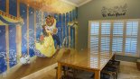 Dining area with large dining table & 8 chairs - Beauty & Beast theming and views onto pool deck with this Orlando Villa for rent direct from owner